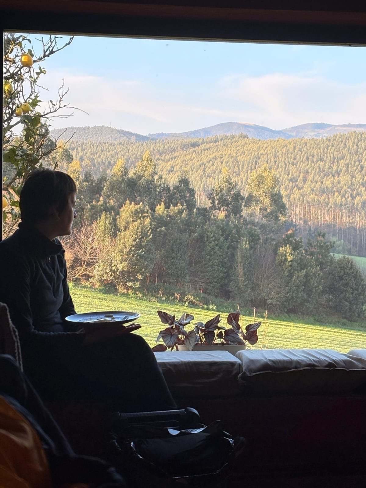 Mujer desayunando frente al paisaje asturiano